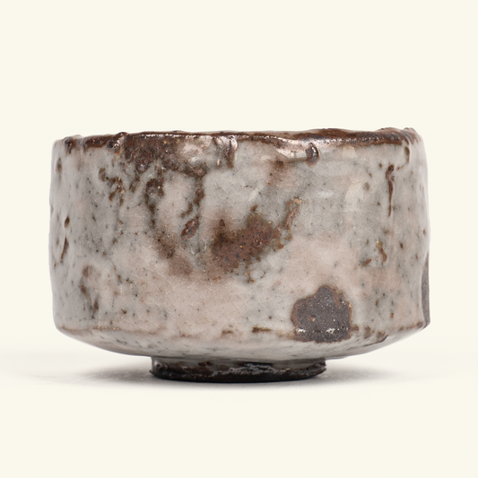 A handmade ceramic bowl with a rustic, hand-painted glaze featuring mottled brown, beige, and gray tones, set against a plain off-white background.