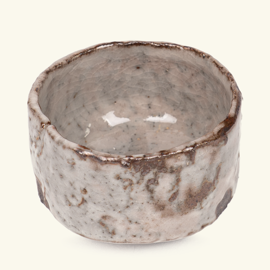 A handmade ceramic bowl with a textured, rustic finish, featuring a speckled gray and beige glaze with dark brown accents on the rim and outer surface, set against a plain off-white background.