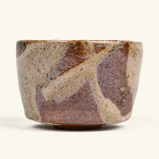 A handmade ceramic bowl with a textured, speckled glaze in earthy brown and beige tones, photographed against a clean off-white background.